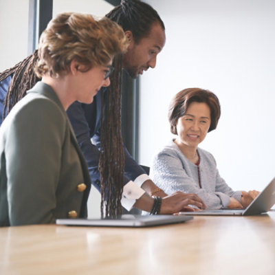 A person's sitting at a table with a laptop in front of them.