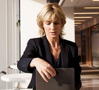 A woman in a suit looking down at a laptop.
