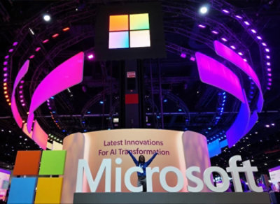 Stand Microsoft con un logo di grandi dimensioni e pannelli LED colorati, che mostrano "Latest Innovations for AI Transformation" (Innovazioni più recenti per la trasformazione dell'intelligenza artificiale).